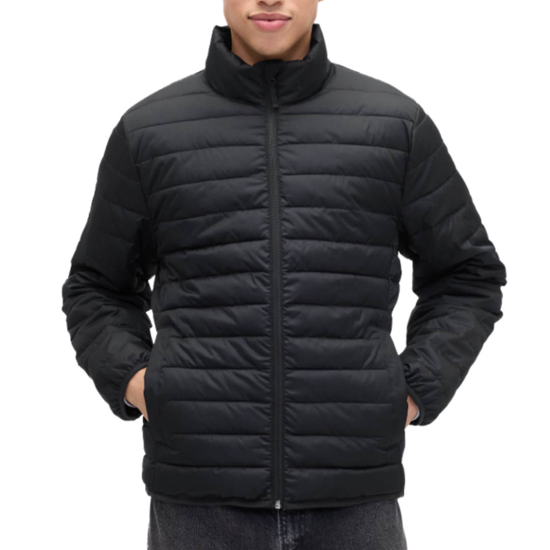 A person is wearing a black quilted jacket with a front zipper and standing with hands in pockets.