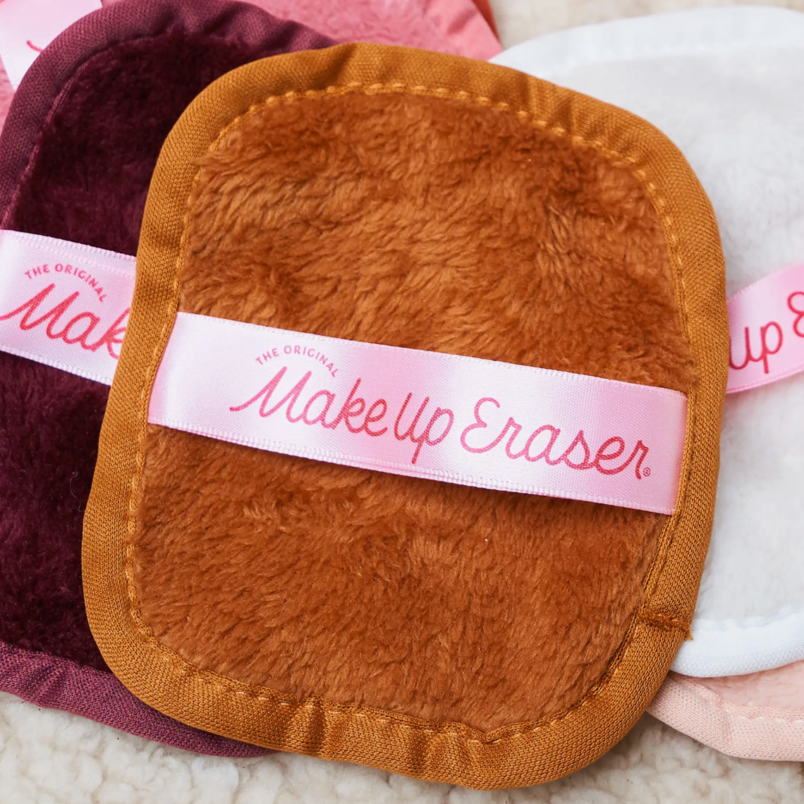Three makeup eraser cloths in different colors with a label reading \“The Original Makeup Eraser.\“