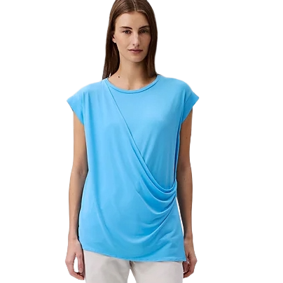 A woman wearing a sky blue short-sleeved, draped top paired with white pants.