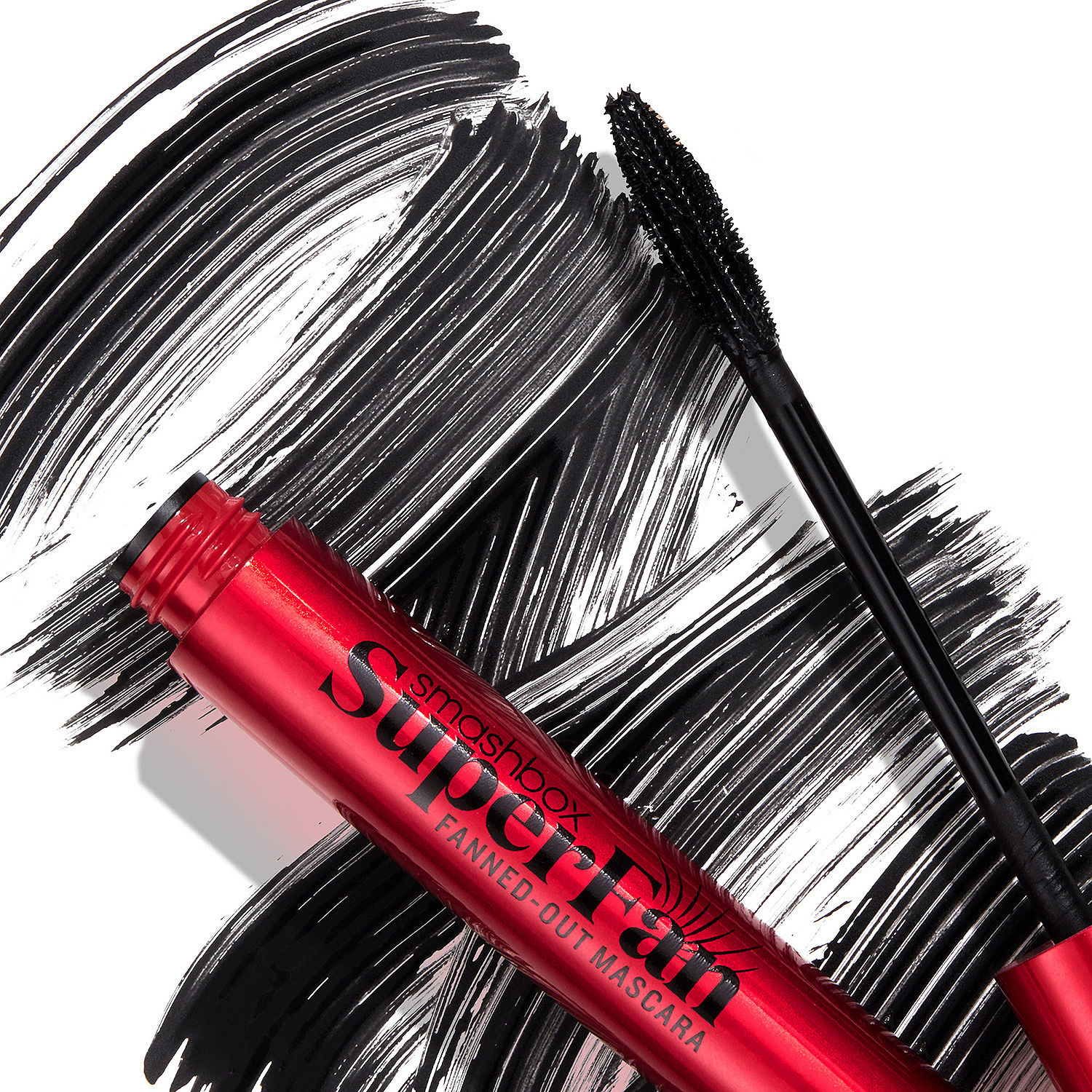 Mascara with a red tube labeled \“Smashbox Super Fan\“ and a black wand applicator, against a background with black brushstroke patterns.