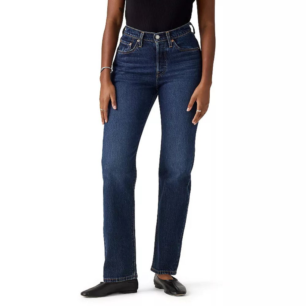A person wearing high-waisted, dark blue straight-leg jeans with a black top and black shoes.