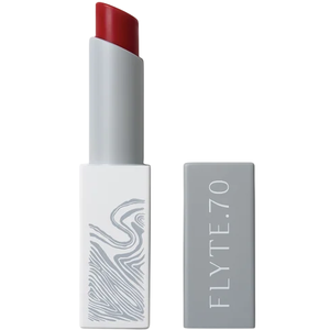 A tube of FLYTE.70 lipstick in a gray rectangular case with a red shade and abstract line design on one side.