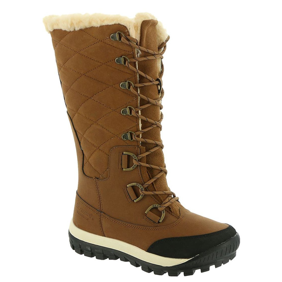 A tall, brown winter boot with quilted stitching, faux fur lining, and a durable rubber sole, featuring D-ring lace hooks for added stability.