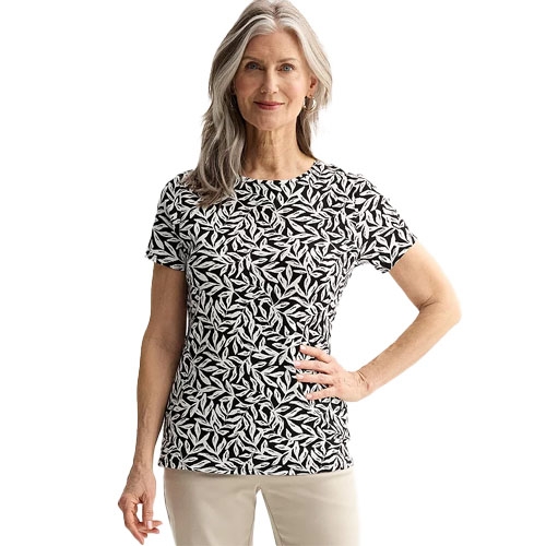 A woman is wearing a short-sleeve, black and white leaf-patterned top with beige pants.