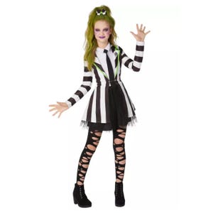 A person is wearing a black and white striped costume with green hair accessories and ripped leggings.
