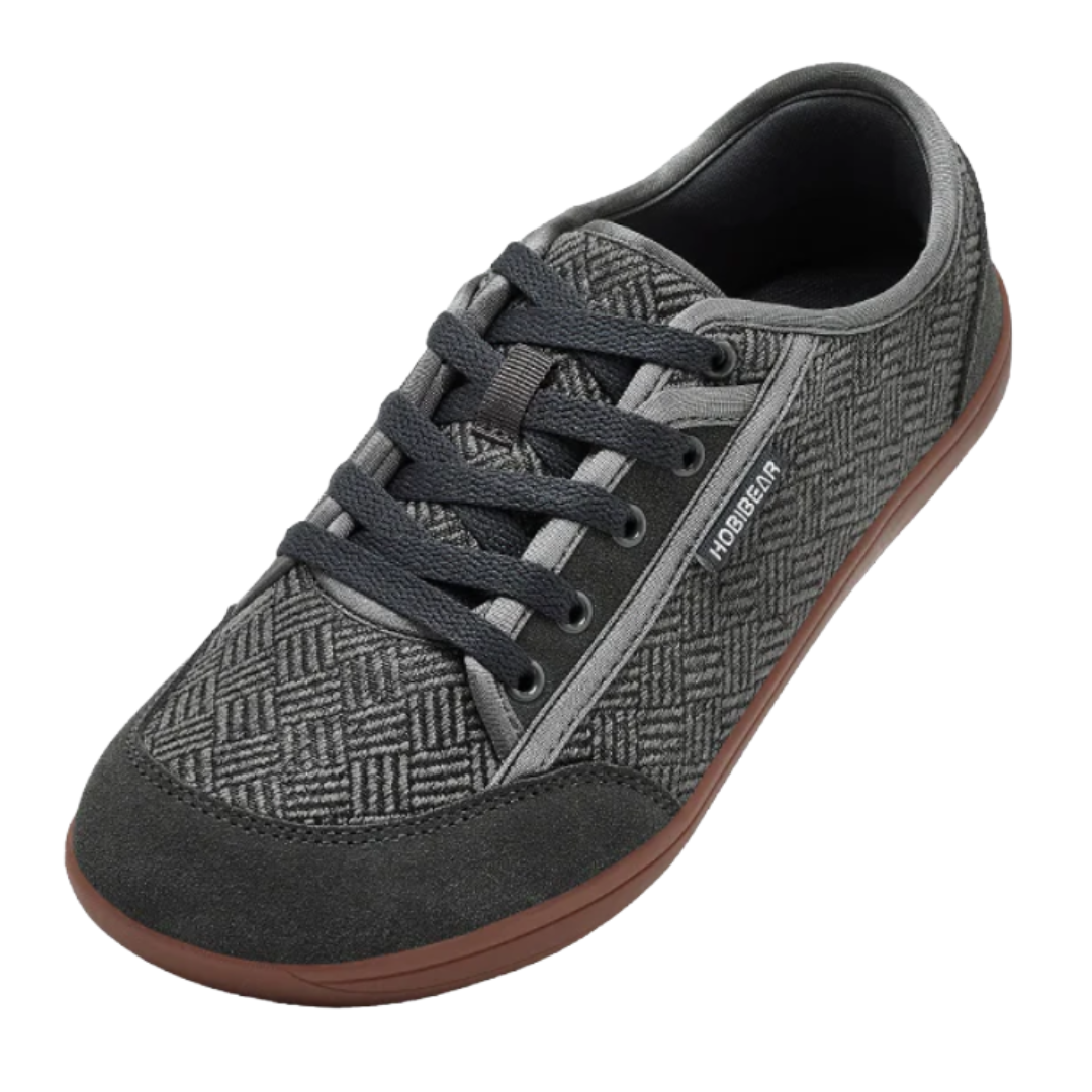A casual lace-up shoe with a geometric patterned fabric, dark grey suede accents, and a brown rubber sole.