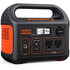 This is a portable Jackery Explorer 300 power station featuring an LCD display, multiple output ports including USB and AC, and an orange and black design with a carry handle.