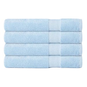 A stack of four light blue bath towels with a simple border design.