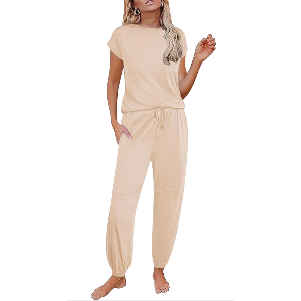 A woman is wearing a beige loungewear set, featuring a short-sleeve top and drawstring pants with elastic cuffs.