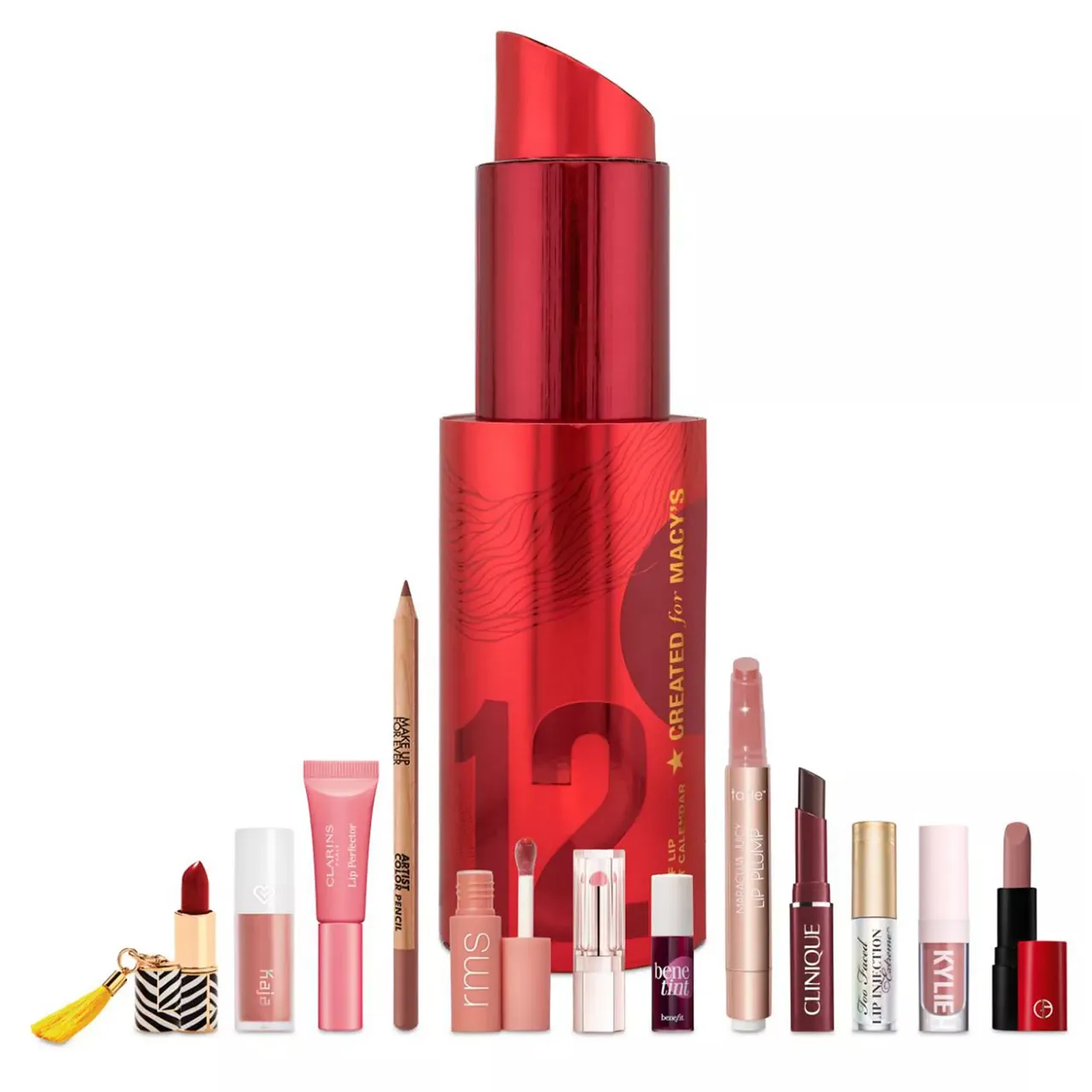 A collection of various lip products including lipsticks, glosses, a lip pencil, and tint from brands like RMS, Clinique, and Kylie, with a large red lipstick-shaped item marked \“12 Days of Beauty Created for Macy's\“ in the background.