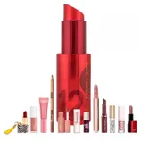 A collection of various lip products including lipsticks, glosses, a lip pencil, and tint from brands like RMS, Clinique, and Kylie, with a large red lipstick-shaped item marked \“12 Days of Beauty Created for Macy's\“ in the background.