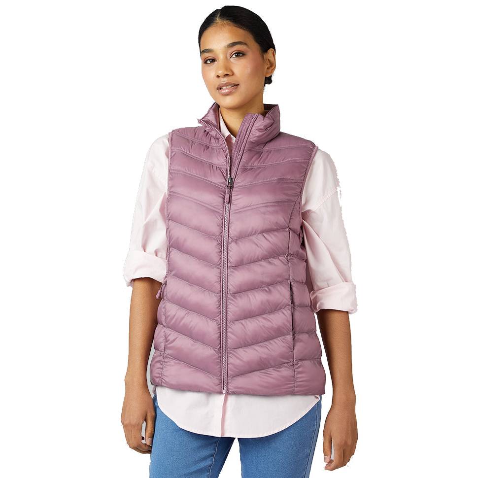 A woman wears a puffed, mauve-colored vest over a light pink shirt, paired with blue jeans.