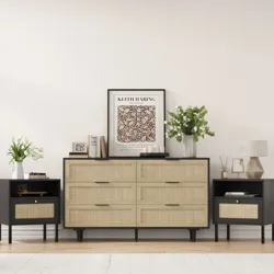 Mid-century style setup with a large dresser and two matching side tables featuring woven rattan drawer fronts and black accents. Decor includes a Keith Haring artwork, books, candles, a lamp, and vases with flowers.