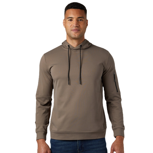 A man wears a brown hoodie with black drawstrings and a zippered pocket on the sleeve, paired with blue jeans.