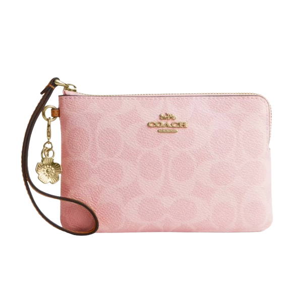 A pink Coach wristlet with gold hardware and a floral charm, featuring a subtle embossed pattern and detachable leather strap.