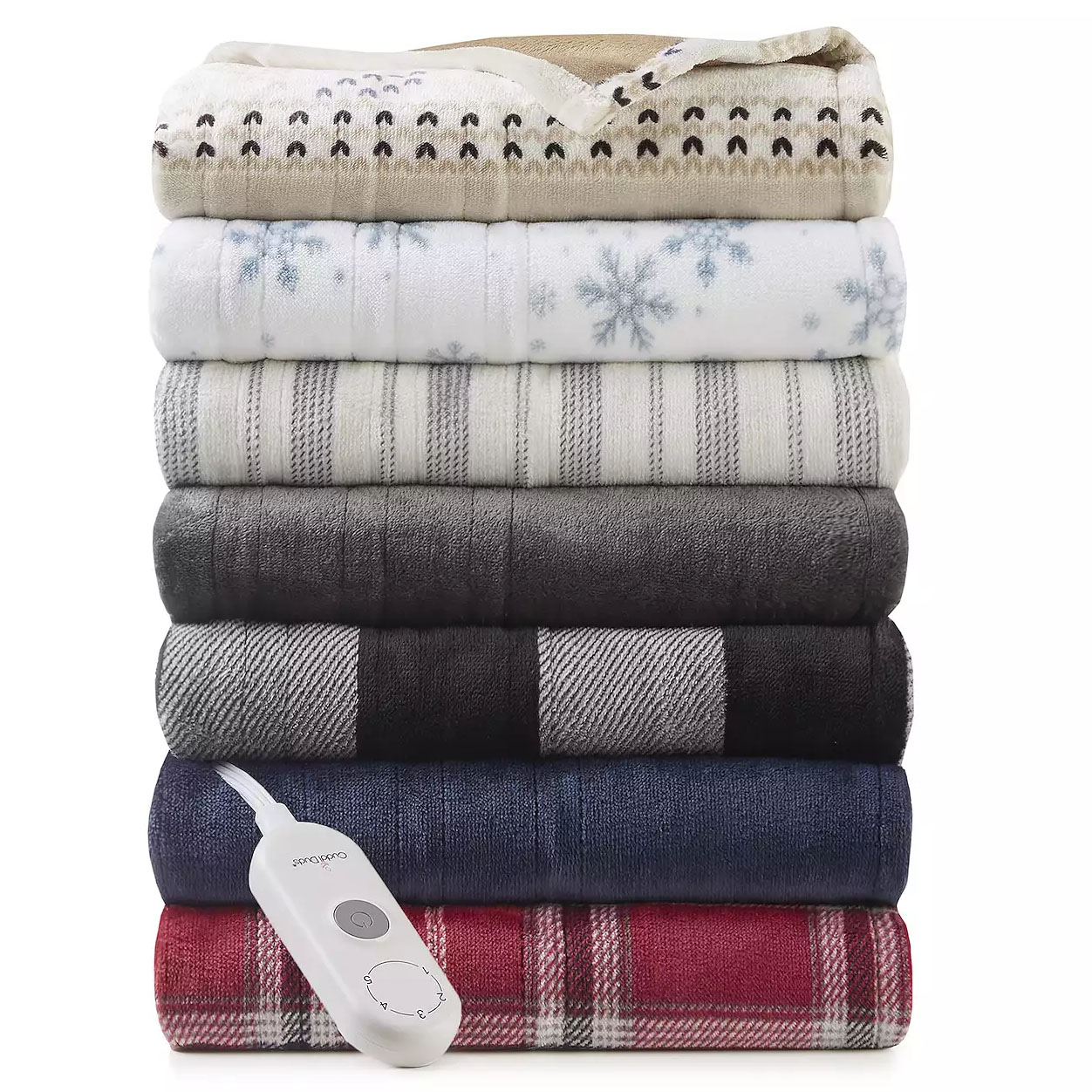 A stack of Cuddl Duds Heated Throws in various colors and patterns with a remote control for adjusting heat settings. The blankets include designs like snowflakes, stripes, and plaids, in shades of beige, white, gray, black, blue, and red.