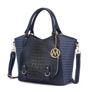 A navy-blue handbag featuring a central textured black panel, gold hardware, an \“M\“ charm, and a detachable crossbody strap. The sides display a repeating \“M\“ pattern in lighter blue.