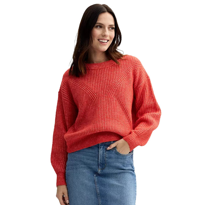 Woman wearing a red textured sweater with geometric patterns and a blue denim skirt.