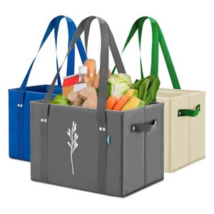 Three colorful reusable grocery bags are displayed, each with long straps and a leaf design, containing groceries like vegetables and packaged goods. Bags in blue, gray, and beige hues with matching handles are visible.