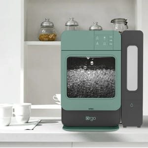 A countertop dishwasher in teal color with a clear window, next to a sleek black water purifier.
