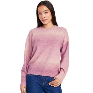 A woman is wearing a pink ombre sweater paired with blue jeans.