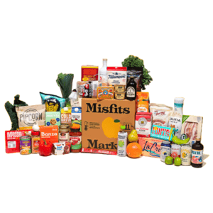 A selection of groceries and snacks with a \“Misfits Market\“ box, featuring popcorn, cold brew, canned goods, pasta, fresh produce, and various beverages like La Croix and kombucha.