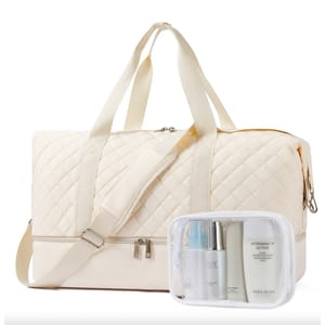 A quilted white weekender bag with a zip-top closure and detachable shoulder strap next to a transparent toiletry pouch containing skincare products.