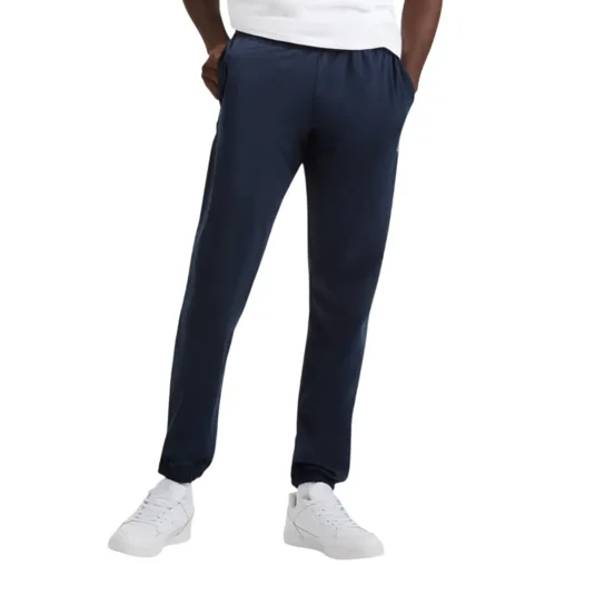 A man is wearing a white Champion t-shirt, navy jogger pants, and white sneakers, posing against a plain background.