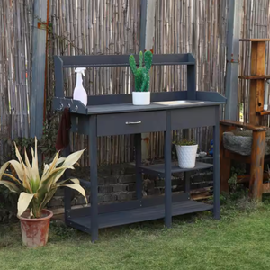 A dark gray gardening table with shelves and hooks, accompanied by a spray bottle, a cactus plant, and two other potted plants.