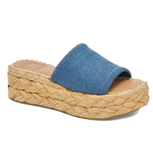 A platform slide sandal with a denim strap and woven straw-like sole.