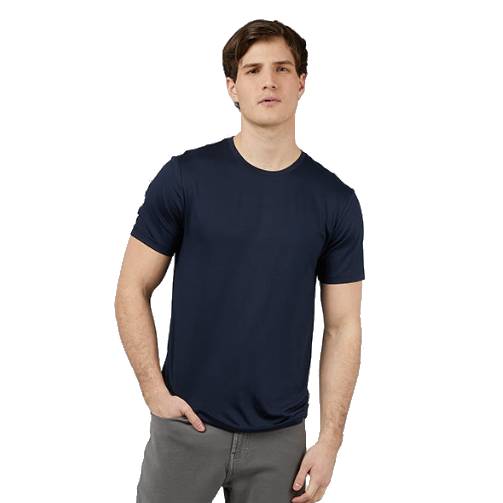 A man wearing a plain navy blue t-shirt and gray pants, standing with one hand in his pocket against a white background.