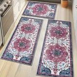 Three oriental-style runner rugs with floral patterns in red, blue, and white are displayed on a light wood kitchen floor, surrounded by white cabinetry and a stainless steel stove.