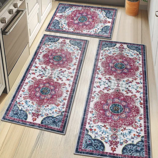 Three oriental-style runner rugs with floral patterns in red, blue, and white are displayed on a light wood kitchen floor, surrounded by white cabinetry and a stainless steel stove.