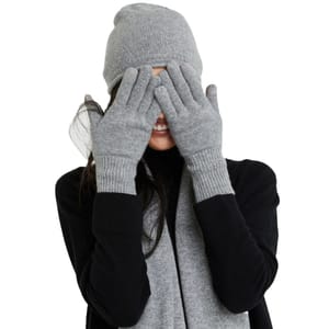 The gloves are made from soft Mongolian cashmere, featuring a ribbed knit design and a grey color, matching the beanie and scarf worn by the person in the image.