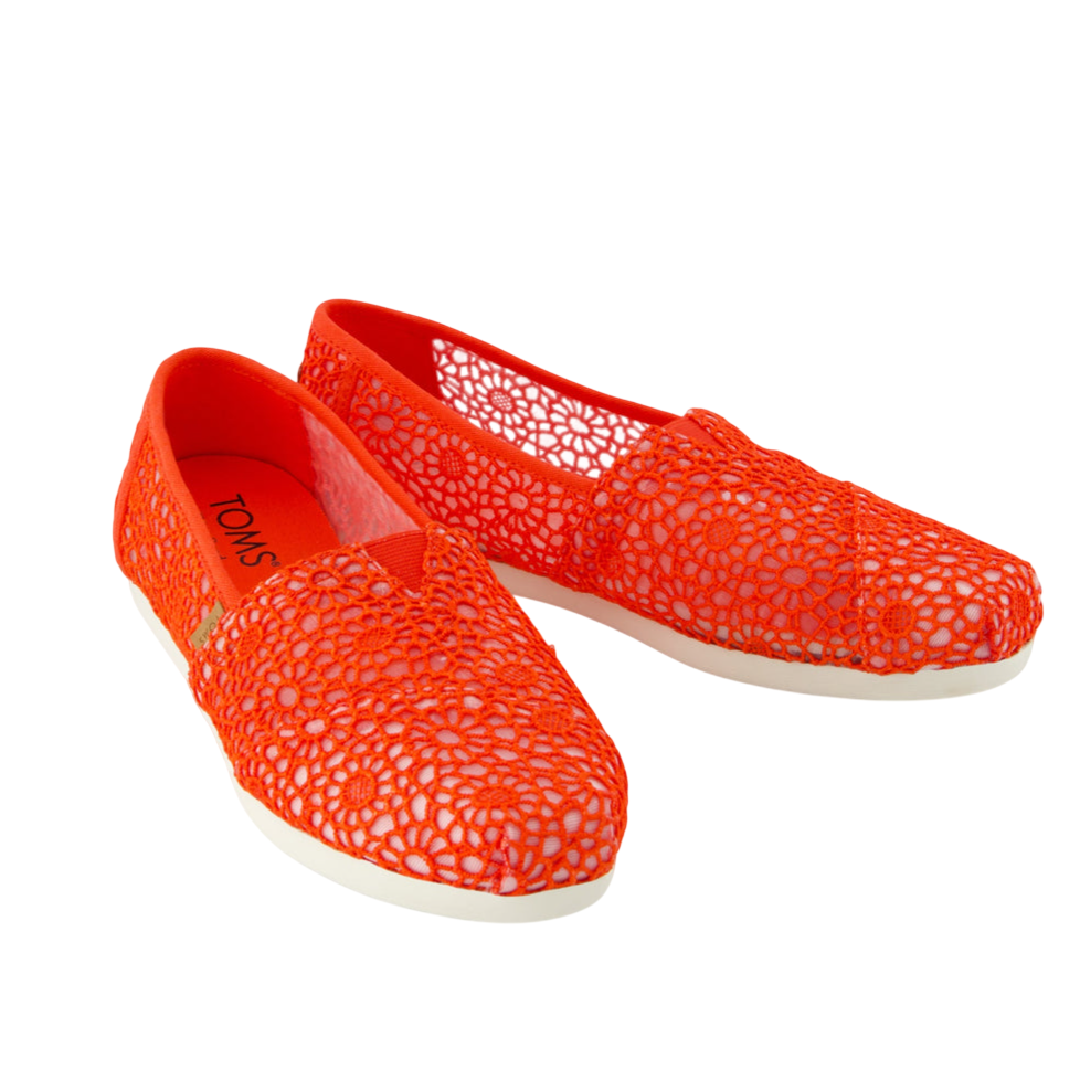 Bright orange crochet slip-on shoes with floral patterns and white soles, featuring the TOMS logo on the insole.