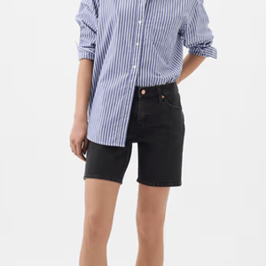 Black denim shorts with a frayed hem, featuring a button and zip closure and classic five-pocket design.