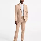 A man is dressed in a stylish tan suit with a single-breasted jacket and matching trousers, paired with a white shirt and brown suede shoes.