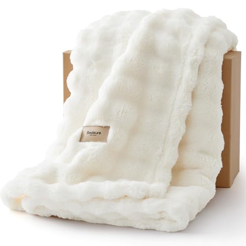 A fluffy, white faux fur blanket with a small label reading \“Bedsure,\“ draped over a brown box.