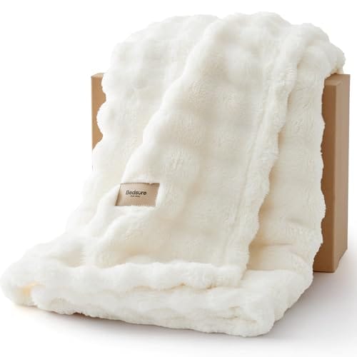 A fluffy, white faux fur blanket with a small label reading \“Bedsure,\“ draped over a brown box.