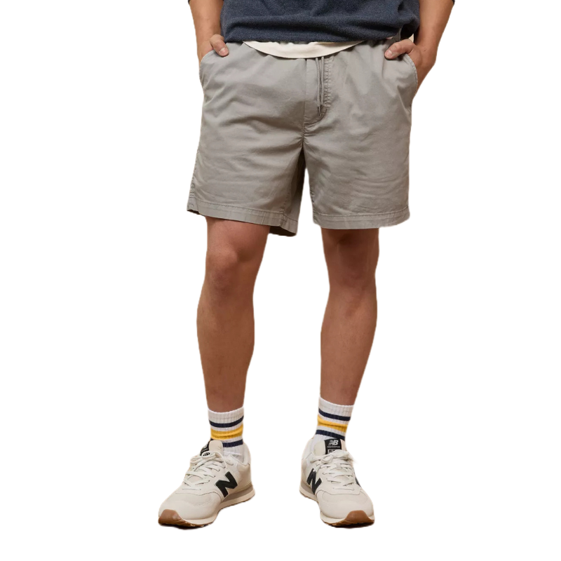 The Flex Lived-In Trekker Short is a pair of light gray shorts with a relaxed fit, featuring hand pockets, paired with striped socks and beige sneakers.