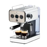 Emeril Lagasse espresso machine with dual spout, stainless steel finish, and a steam wand. Two small glass cups filled with espresso are placed under the portafilter.