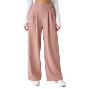 Wide-legged, high-waisted pink trousers with pleats and two side pockets, paired with a white long-sleeve top and white sneakers.