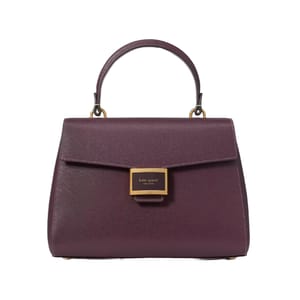 A maroon leather handbag with a structured design features a top handle and a front flap secured by a gold rectangular clasp labeled \“kate spade new york.\“