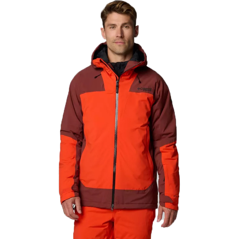 A man is wearing a two-tone orange and brown Columbia ski jacket and matching orange pants.