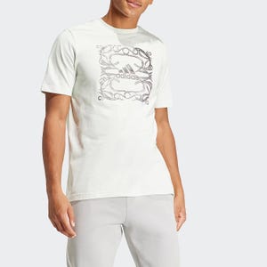 A man is wearing a white short-sleeved T-shirt with an ornate graphical print around the Adidas logo.