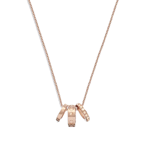 A rose gold-tone necklace featuring a delicate chain and three miniature rings as pendants, adorned with signature engravings and embellishments.