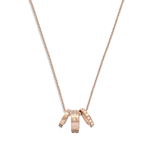 A rose gold-tone necklace featuring a delicate chain and three miniature rings as pendants, adorned with signature engravings and embellishments.