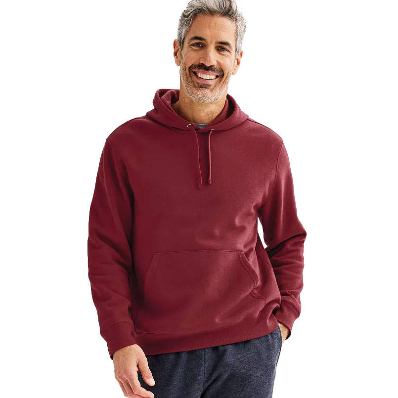 A man wearing a maroon hoodie with a front pocket and drawstring, paired with dark pants, smiling against a plain background.