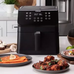 A black 5.8-quart Cosori air fryer with a digital control panel is displayed on a kitchen counter, surrounded by cooked food.