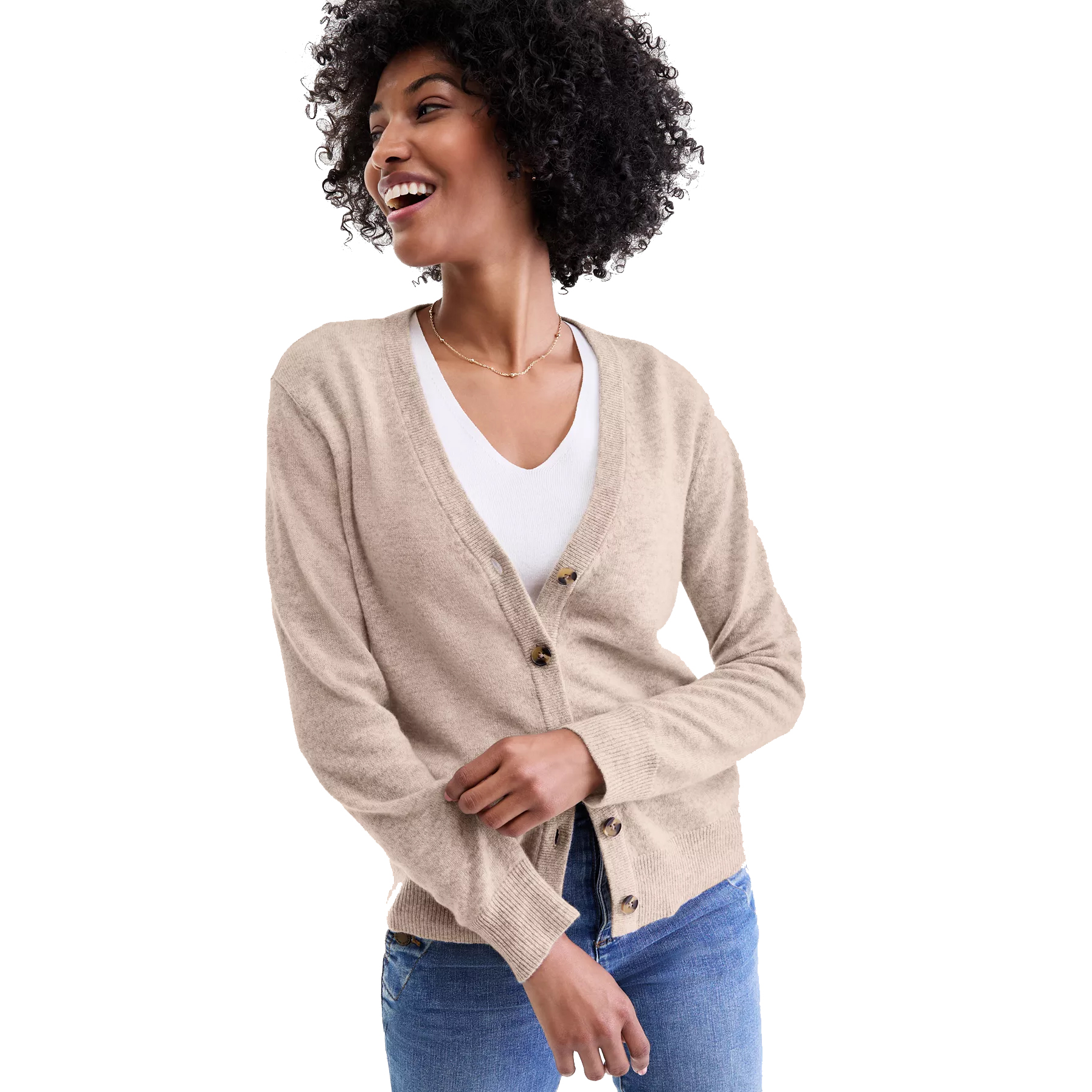 A woman is wearing a beige V-neck cardigan with brown buttons, over a white top, paired with blue jeans.